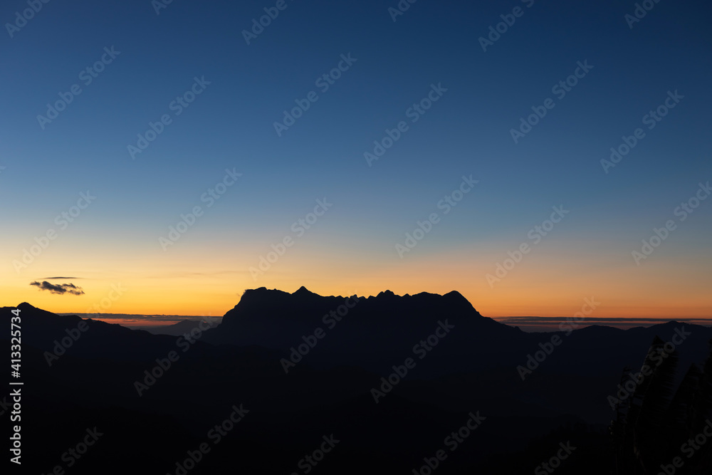 Heaven at early morning with copy space and silhouette mountains.Predawn clear sky with orange horizon and blue atmosphere. Smooth orange blue gradient of dawn sky. Heaven at early morning with copy space and silhouette mountains.Predawn clear sky with orange horizon and blue atmosphere. Smooth orange blue gradient of dawn sky.