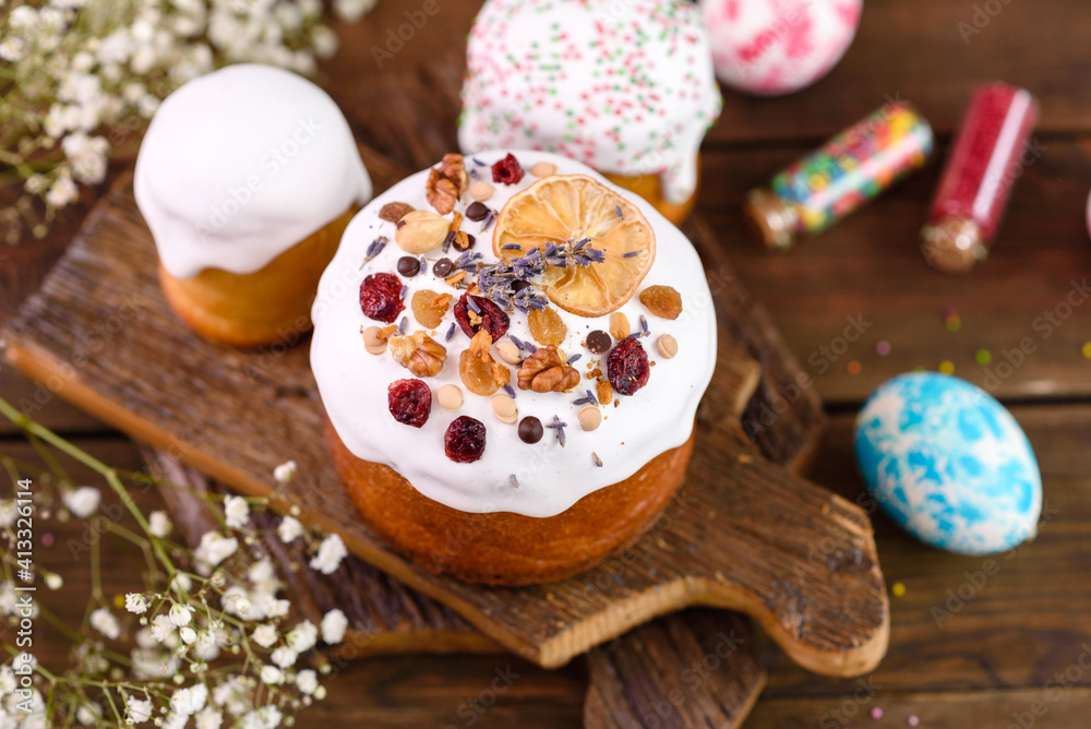 Festive cakes with white glaze, nuts and raisins with Easter eggs on the festive table Festive cakes with white glaze, nuts and raisins with Easter eggs on the festive table