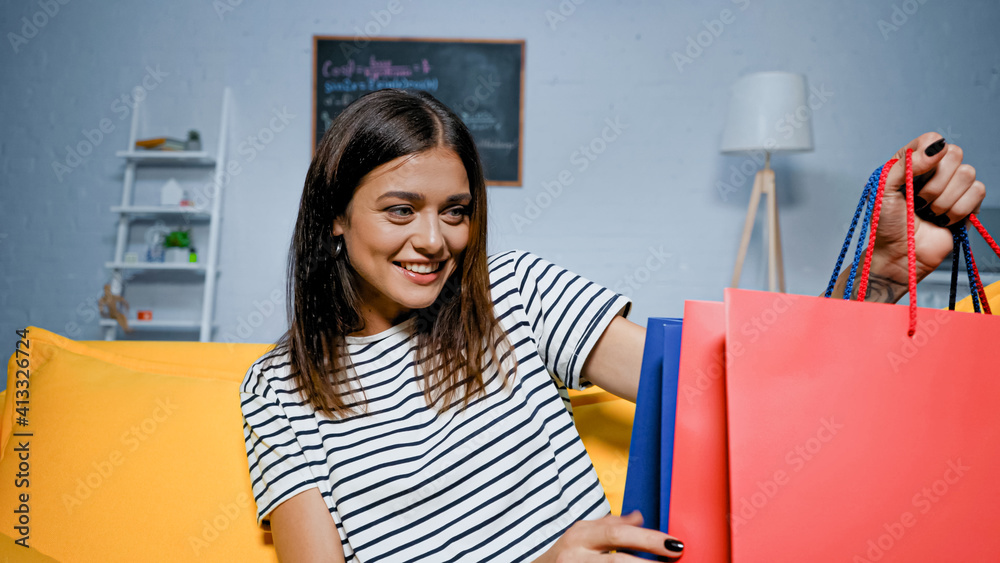 Happy woman looking at shopping bags with purchases at home Happy woman looking at shopping bags with purchases at home