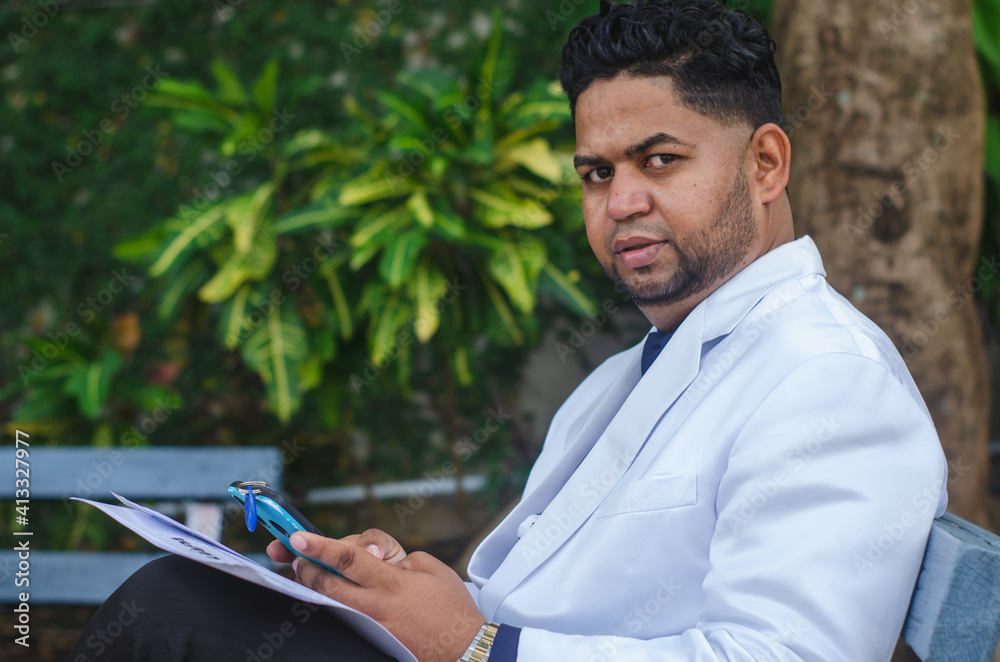 man in suit and white jacket sitting on a bench in the park sending a message with papers in hand, of Latino Dominican origin, businessman man in suit and white jacket sitting on a bench in the park sending a message with papers in hand, of Latino Dominican origin, businessman