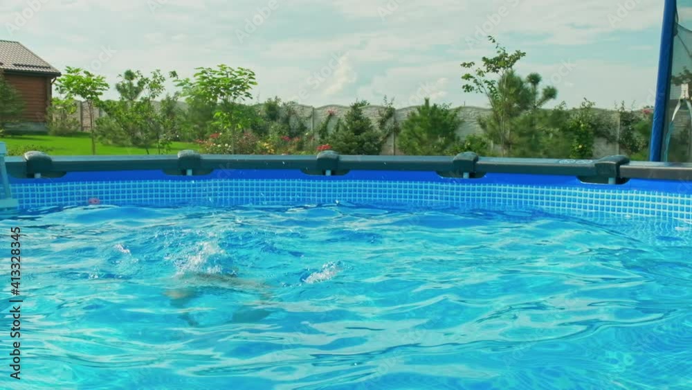 Slow motion clip: Happy boy having fun in the private pool. White boy jumps into the pool creating a big splash. Child dives into the water in summer. Activity of the child in the water. Happiness Slow motion clip: Happy boy having fun in the private pool. White boy jumps into the pool creating a big splash. Child dives into the water in summer. Activity of the child in the water. Happiness