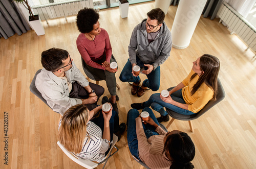 Diverse group of people sitting in circle in group therapy session.