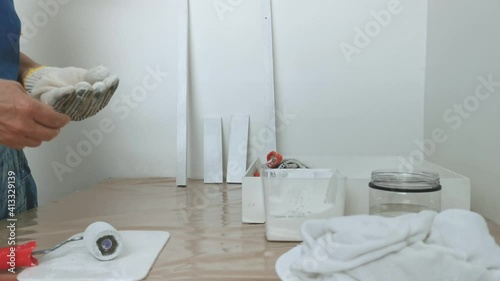 Woman taking off her painting gloves. Painting white on wood using a spWoman taking off her painting gloves after painting white on wood using a sponge roller. Close up.onge roller. Close up. photo