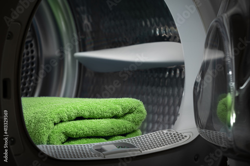 Fotografia Folded clean green towels in the tumble dryer