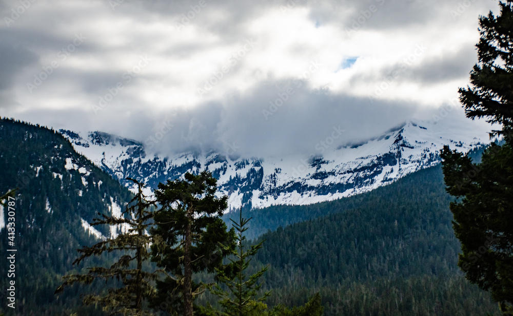 Mountains in the snow, overgrown with wood. Thick clouds over the mountains. Montana