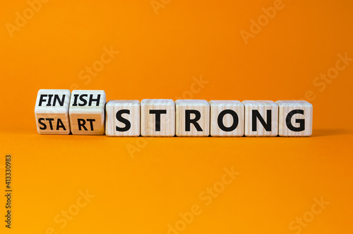 Start and finish strong symbol. Turned wooden cubes, changed words 'start strong' to 'finish strong'. Beautiful orange background, copy space. Business and start and finish strong concept.