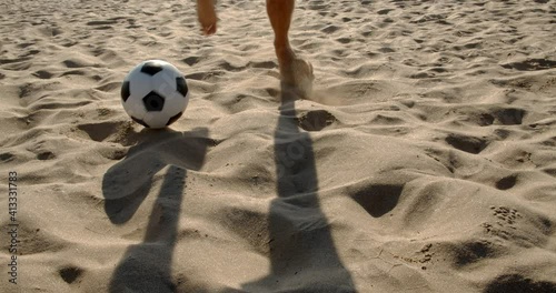 Football soccer game on the beach. Male feet leading the ball on the sandy sea beach, 4k slow motion
