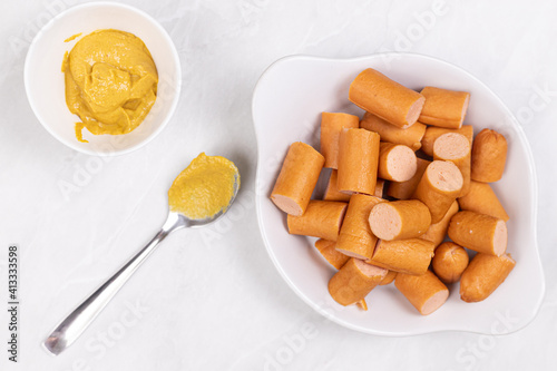 Sliced Cooked Hot Dogs served on the plate with Mustard photo