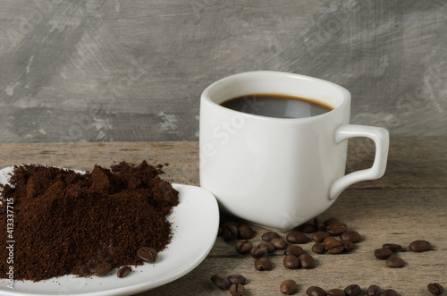 A cup of coffee with coffee beans and ground coffee on a saucer