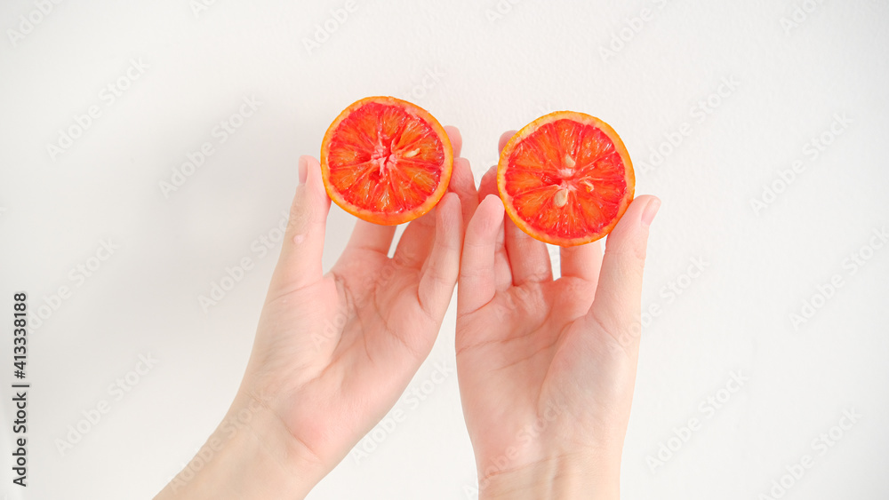 Slice of red blood orange in hands on a wooden table background
