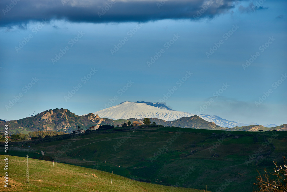 The snowy silhouette of the Etna volcano seen from the countryside of Central Sicily near Nicosia on a beautiful sunny day
