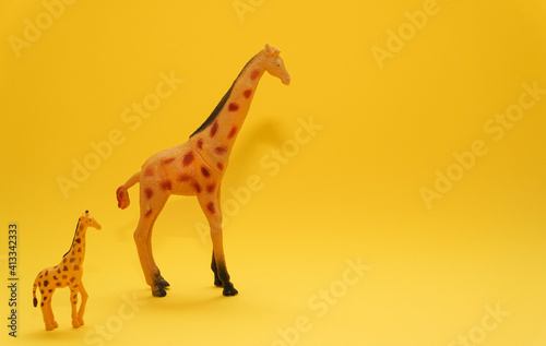 Photography Two toy giraffes on bright yellow color background
