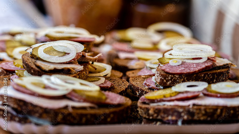 Bread with meat, sausage and onions on a tray in an outdoor cafe. Quick snacks., selective focus