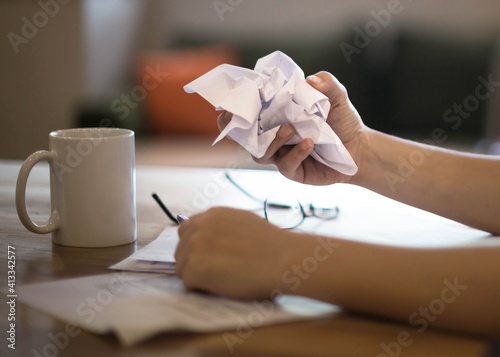 A frustrated discouraged woman crumpling a paper at work on her desk. photo