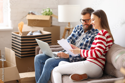 Cheerful couple with laptop discussing insurance of new home