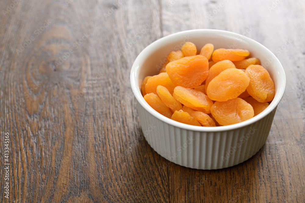 Dried apricots in a ceramic bowl on stained hickory wood planks Dried apricots in a ceramic bowl on stained hickory wood planks