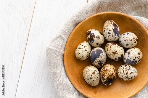 The quail eggs lie on a wooden plate on a white table