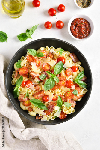 Tomato and bacon pasta with parmesan cheese and basil leaves