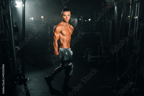 Young sports athlete guy shows muscles in the gym, doing sports, healthy lifestyle.
