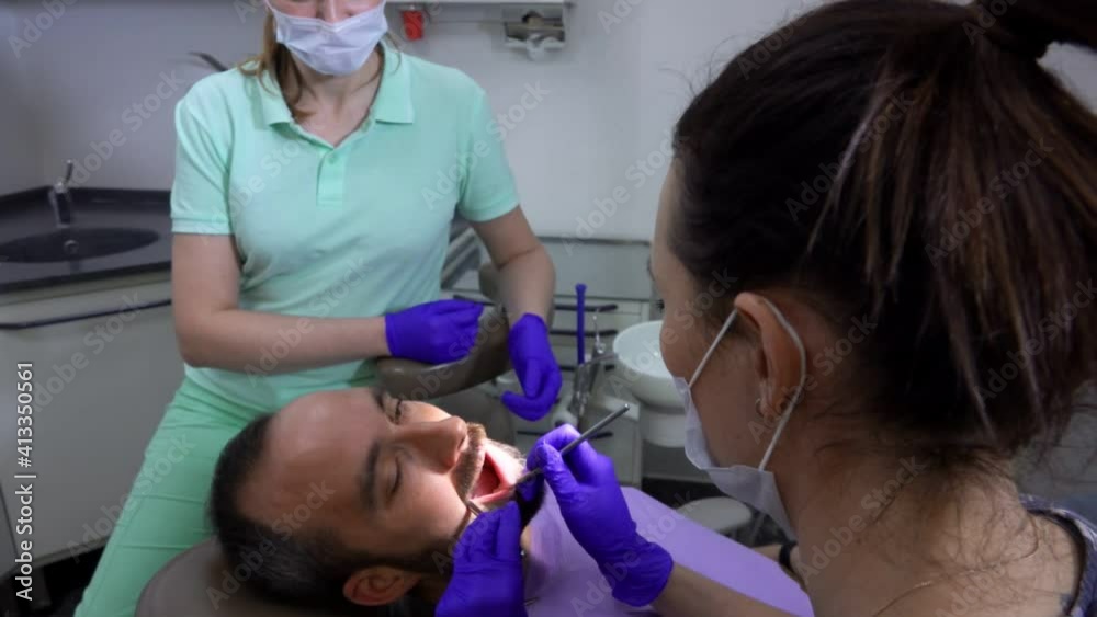 Female dentist is making tooth treatment for a male patient in dental clinic