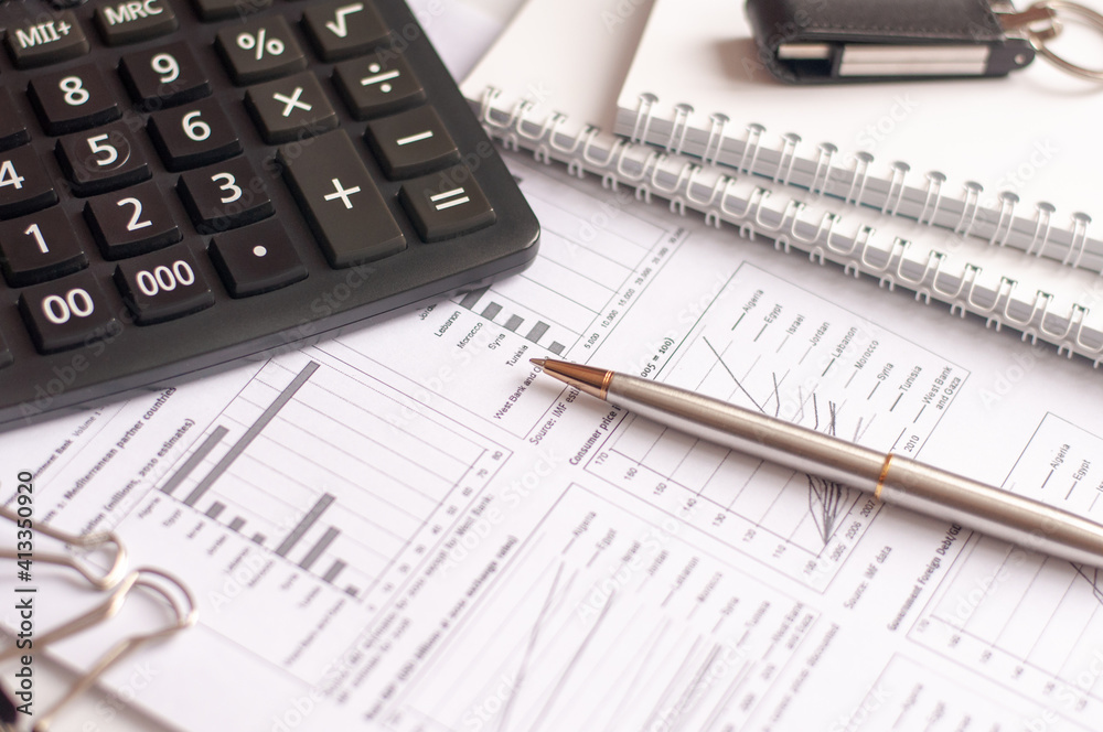 On financial documents with columns of numbers is a black calculator. pen and glasses for vision. Business and financial concept On financial documents with columns of numbers is a black calculator. pen and glasses for vision. Business and financial concept