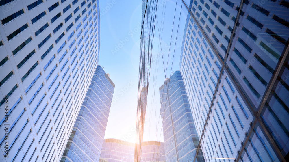 Fototapeta premium Downtown corporate business district architecture. Glass reflective office buildings against blue sky and sun light. Economy, finances, business activity concept. Rising sun on the horizon.