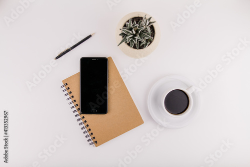 workplace on white background with notepad smartphone flower and pen and cup of coffee