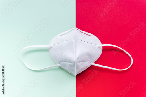 Disposable mask with hook, FFP2 with N95 protection to protect yourself and others from Covid-19. protection against the spread of infection.Light red and green background.Top View