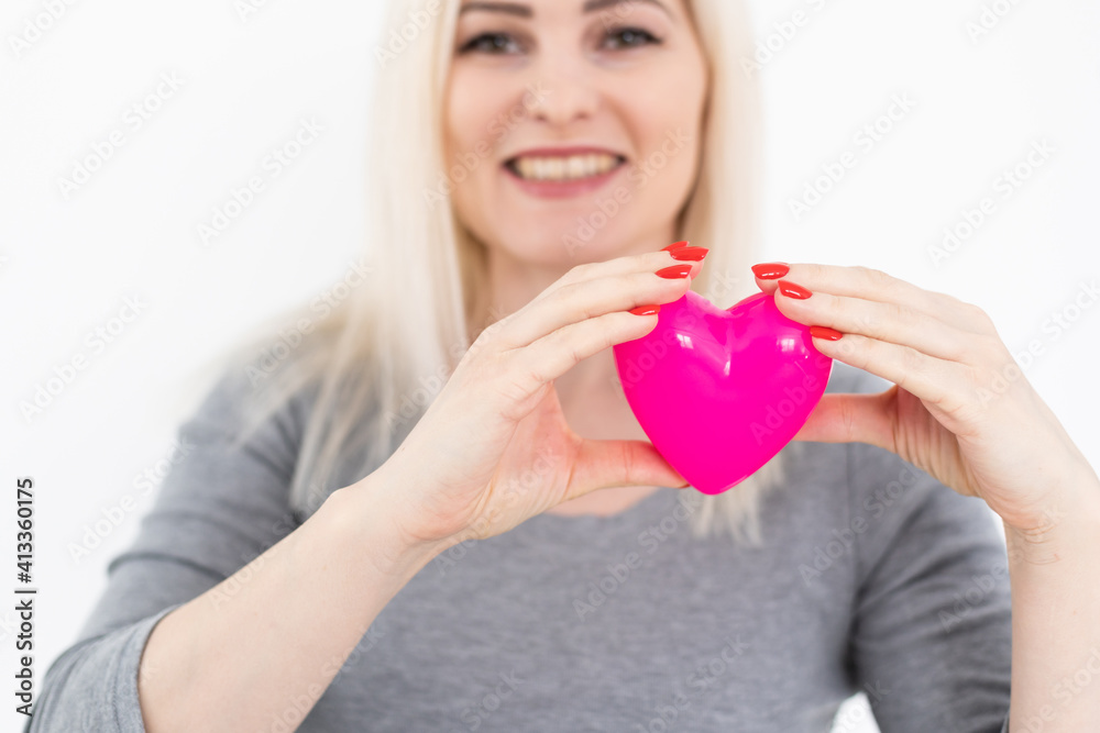 Young happy woman hold Love symbol red heart. Isolated on studio background female model.