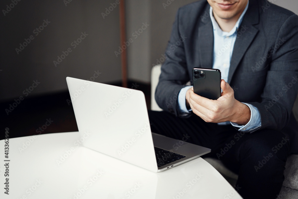 uses a modern social network app. copy space. male hands near the computer laptop. prints a message on the phone. uses a modern social network app. copy space. male hands near the computer laptop. prints a message on the phone.