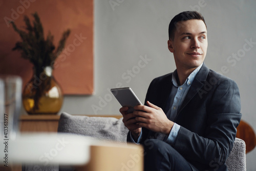 the financier works on a tablet, prints a message in a new messenger. Communicates with project partners, the field of Finance. in a business suit sitting in a modern style office.