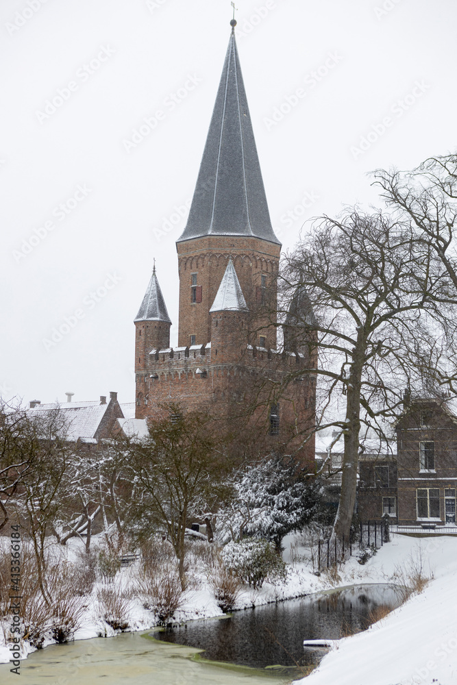 Pointy rooftop tower with cants in winter wonderland landscape part of historic city center of medieval Hanseatic town during a snowstorm