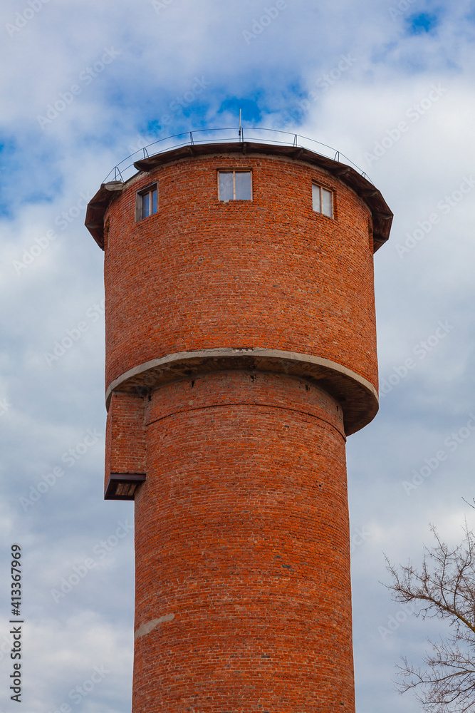 Old brick water tower against cloudy sky background