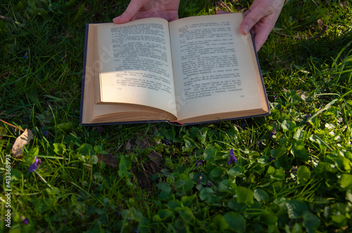 Hands holding a book on the green grass