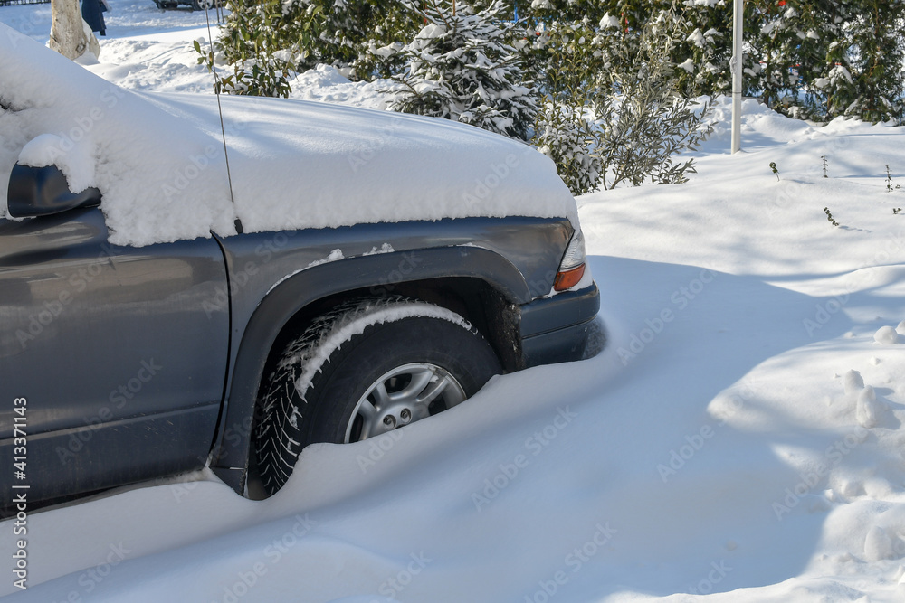 Front part of the big offroad car is  buried in the snow as a result of heavy snowfalls