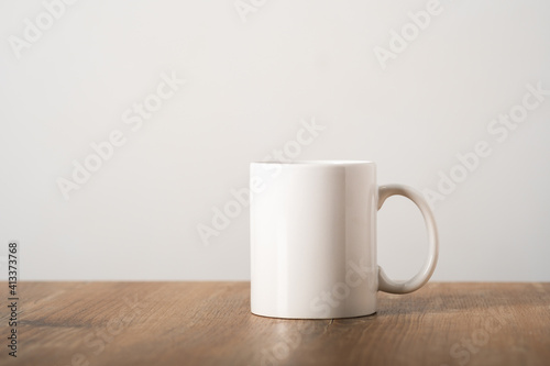 Mockup white mug on a wooden table top in a minimalist Scandinavian interior. Template, layout for your design, advertising, logo with copy space. Cup light beige background