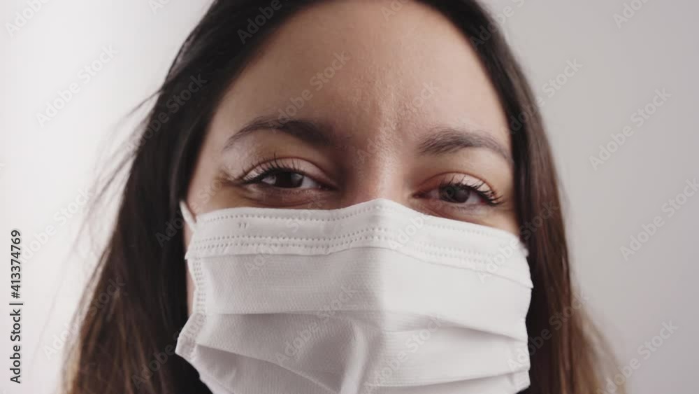Close-up of a woman's face with mask looking at smiling camera indoors. Close-up of a woman's face with mask looking at smiling camera indoors.