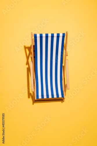 Vászonkép top view of striped deck chair on yellow.