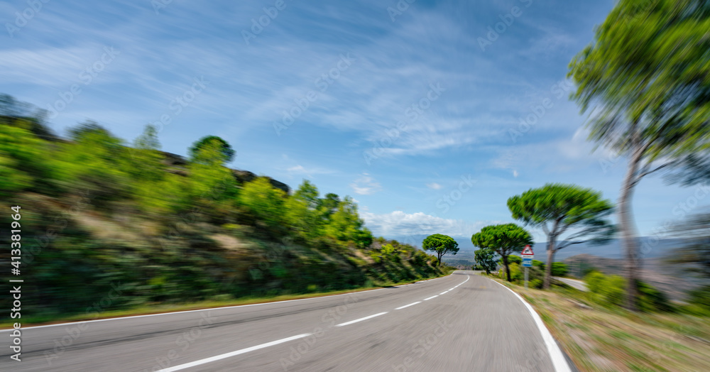 Empty long mountain road to the horizon on a sunny summer day at bright sunset - high speed motion blur effect.