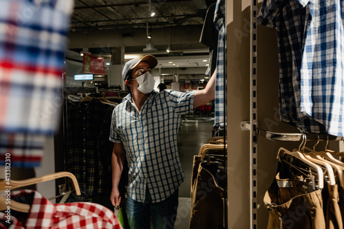 man in a clothing store wearing a medical mask, purchasing