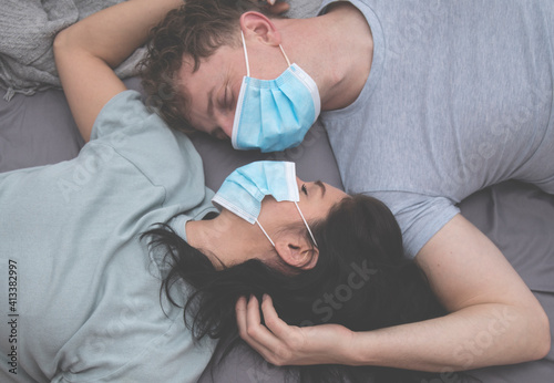 The couple quarreled and lies in bed in medical masks. Family problems due to quarantine isolation due to the coronavirus pandemic. 