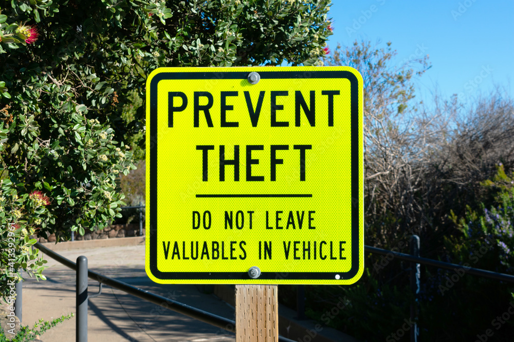 Yellow metal prevent theft sign on wooden post