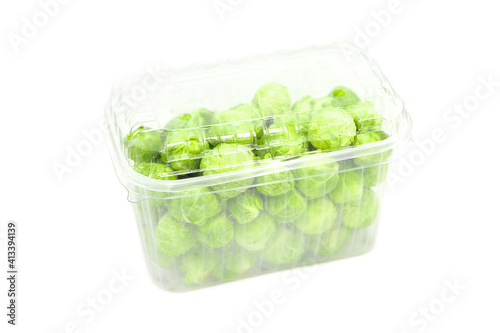 Organic brussels sprouts in disposable plastic container isolated on white background.