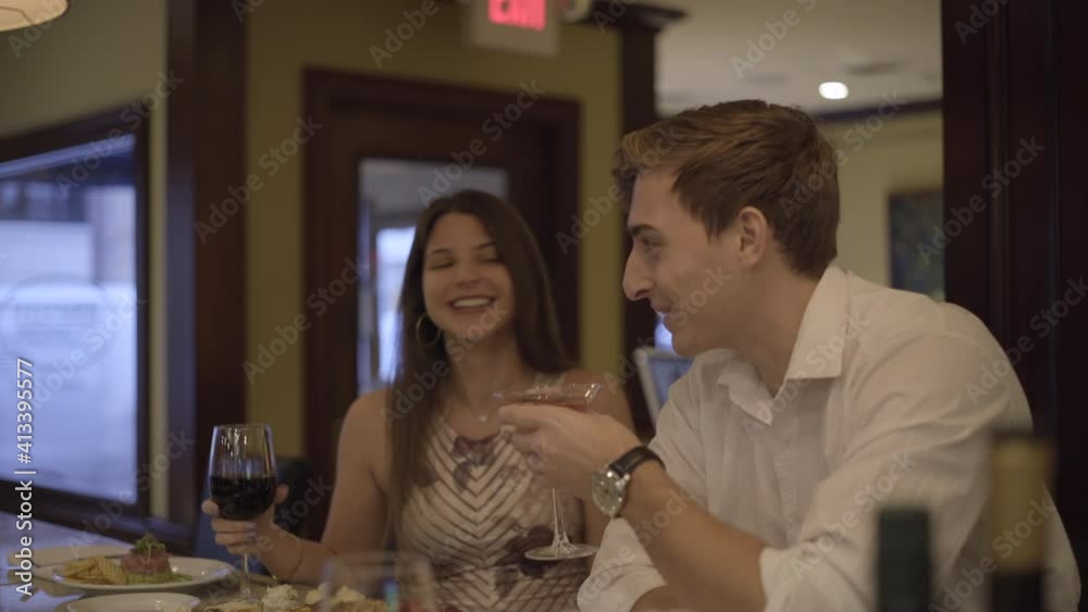 Young Man and Woman Couple Sitting at Bar Counter Talking and Sipping on Drinks Young Man and Woman Couple Sitting at Bar Counter Talking and Sipping on Drinks