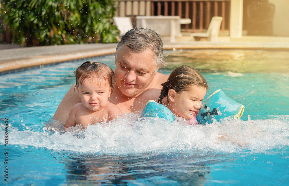 Portrait of grandfather and children in the pool.