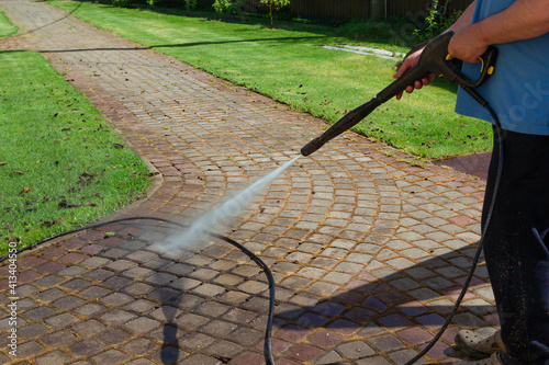 Cleaning street with high pressure power washer, washing stone garden paths photo