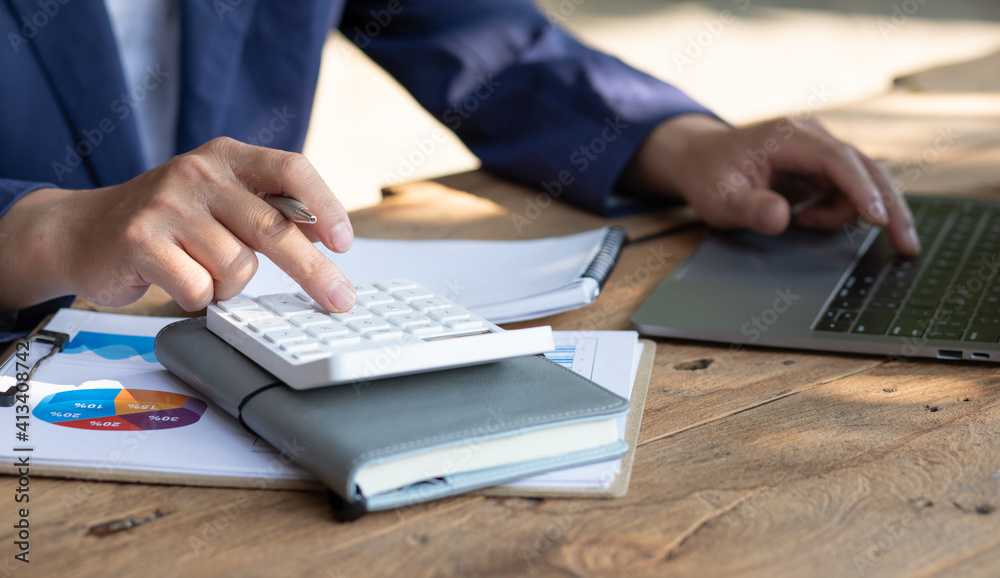 Close up businessman hand using calculator and working with laptop calculate about finance accounting at coffeeshop outdor.finance accounting concept Close up businessman hand using calculator and working with laptop calculate about finance accounting at coffeeshop outdor.finance accounting concept
