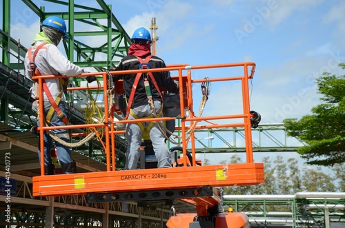 Фотография Worker are driving the Orange articulate boom lift or telescopic boom lifts and bucket crane mounted on truck to safety for working at heights and articulating boom lift reaching high up