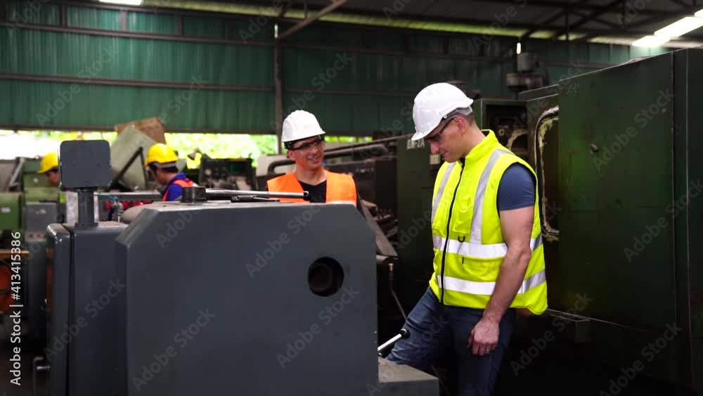 Workers wearing safety hat in a factory. The engineering looks about the machine settings in the factory. Workers wearing safety hat in a factory. The engineering looks about the machine settings in the factory.