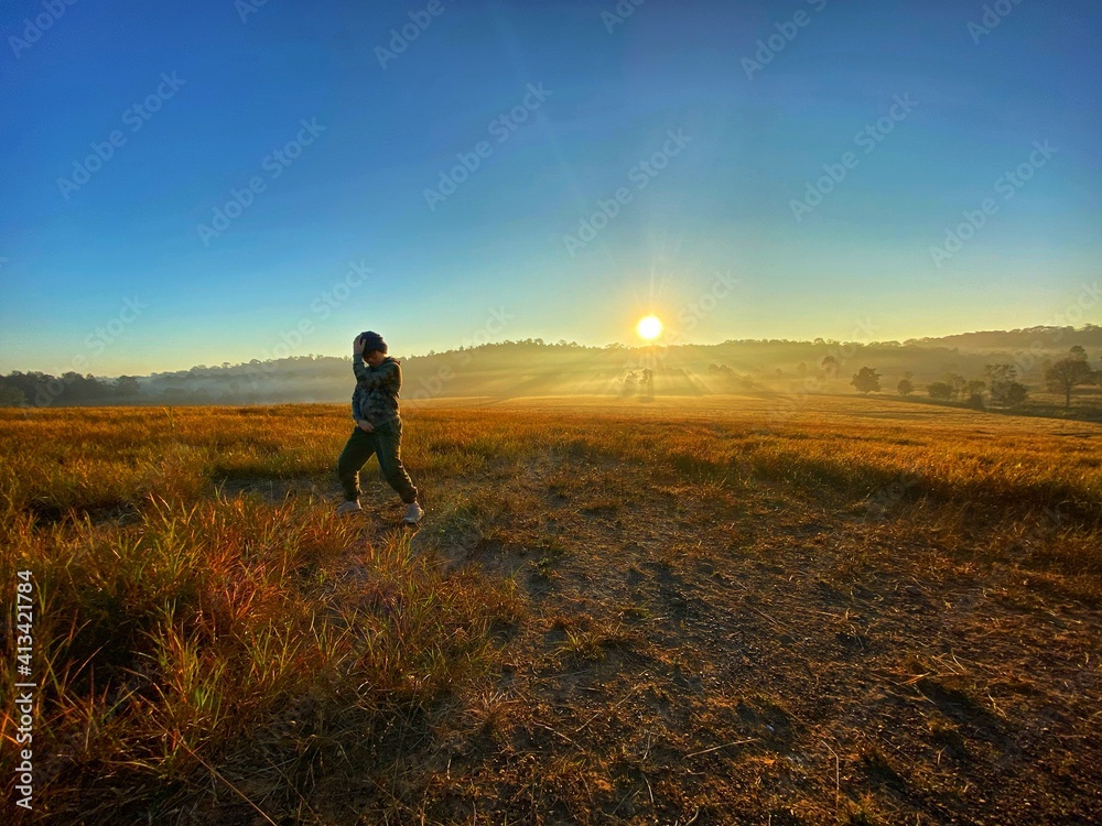 Asian boy  at the field while golden sky in the morning 
